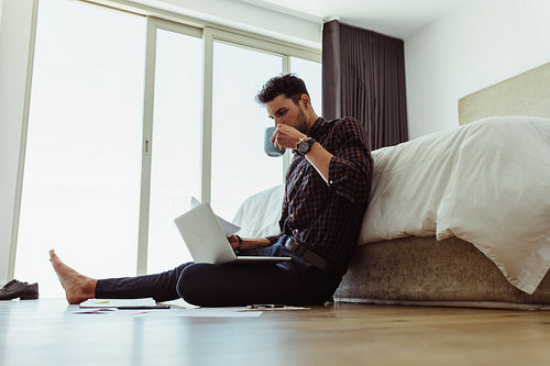 Man working on his laptop sitting on the floor home