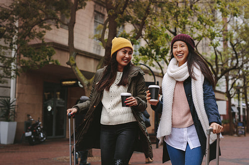 Smiling woman tourists walking around the city drinking coffee