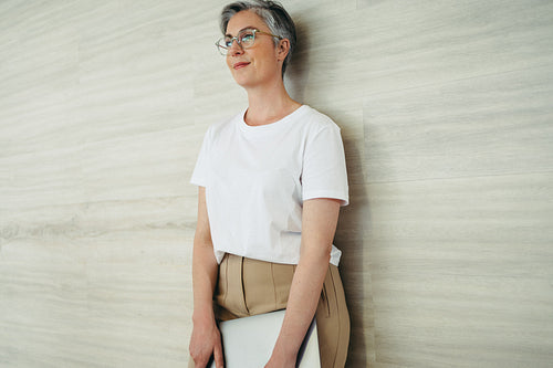 Pensive businesswoman standing against a wall in an office