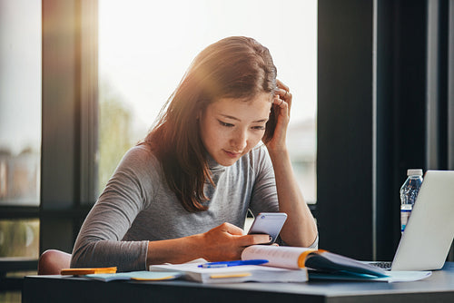 Student using smart phone at college library