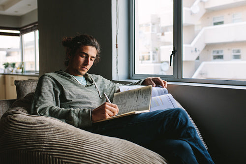 Student studying at home sitting beside a window