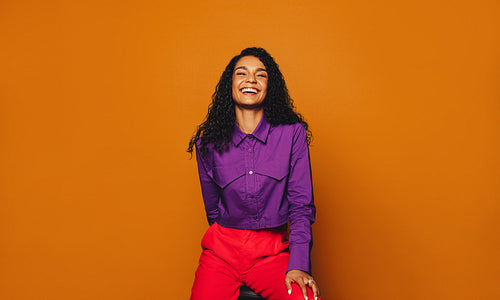 Happy woman with curly hair on orange background, smiling