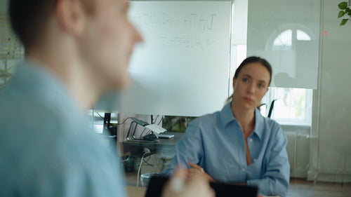 Coworkers discuss work during a business meeting in a bright office