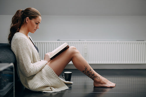 Beautiful young lady reading a novel at home