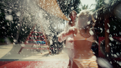 Joyful mother and girl enjoying playful foam party on a sunny summer day