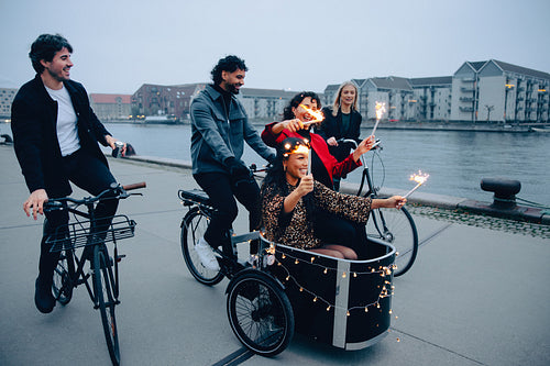 Friends enjoying a festive evening ride with sparklers near the waterfront