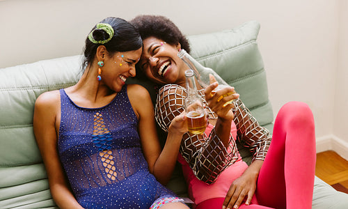 Friends at home laughing together before the carnival on couch