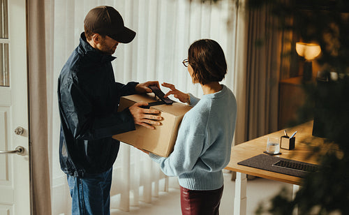 Office package delivery: courier waits as woman signs