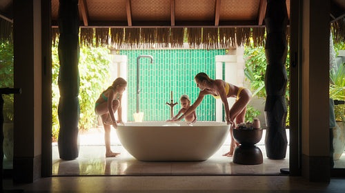 A joyous family vacation moment with mother and children playing in a luxurious resort bathroom