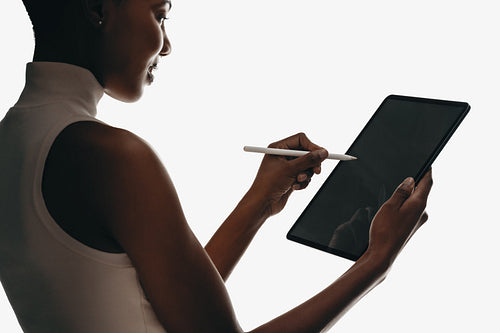 Side view of woman using stylus with tablet in minimalist setting