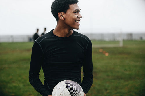 Portrait of a footballer standing on field holding a ball