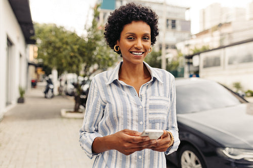 Cheerful young woman using a smartphone outdoors