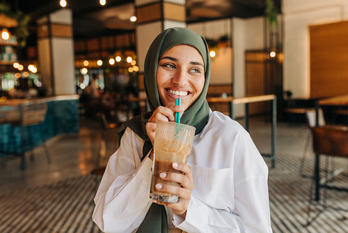 Beautiful woman with a hijab drinking a milkshake in a cafe