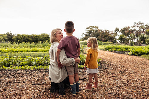 Young single mother talking to her kids on an organic farm