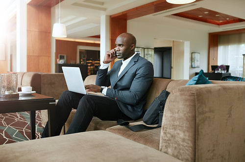 Businessman in hotel lobby using mobile phone