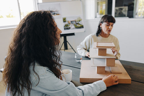 Two female architects presenting a modern design concept for a building model