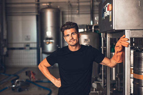 Brewer standing by beer filling machine at brewery factory