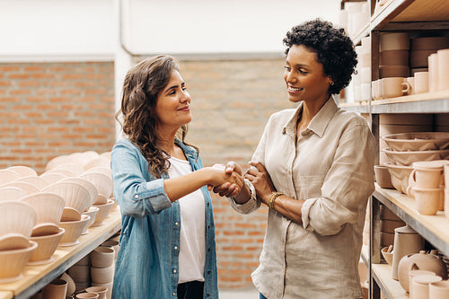 Two female ceramists shaking hands in a ceramic shop