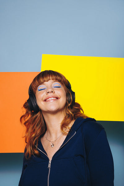 Smiling woman listening to music while standing in front of two advertisement boards