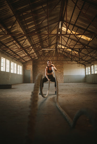Tough female working out with battling ropes