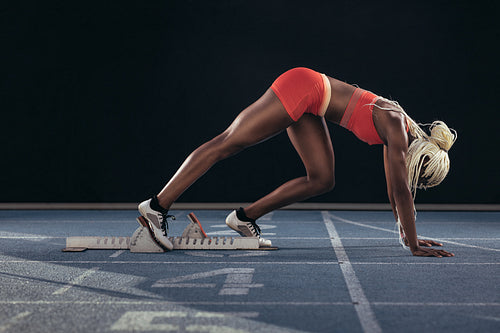 Sprinter using a starting block to start her sprint on a running track