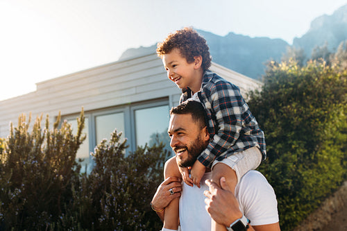 Father carrying his son on his shoulders and walking outdoors