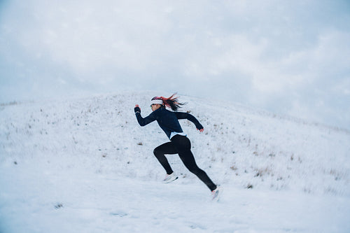 Hill running drives the woman uphill through snow during winter training