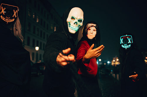 People in illuminated masks celebrating halloween at night in a city setting