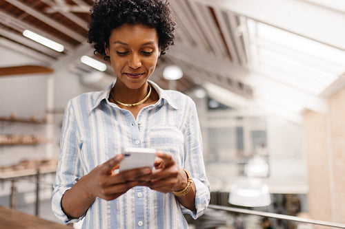 Young small business owner using a smartphone in a warehouse