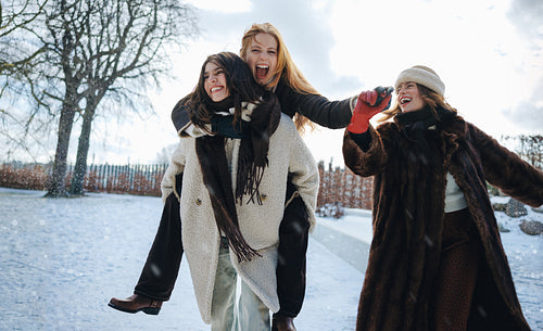 Women laugh during a piggyback ride in the snow
