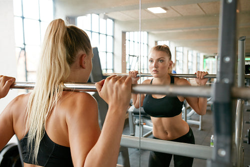 Woman exercising with barbell in gym