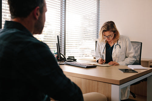 Doctor writing medical history of patient in hospital