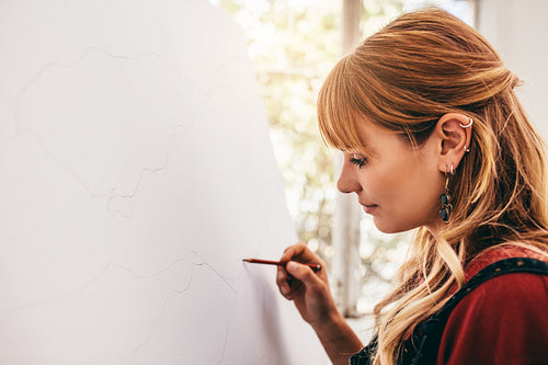 Young woman artist drawing with pencil