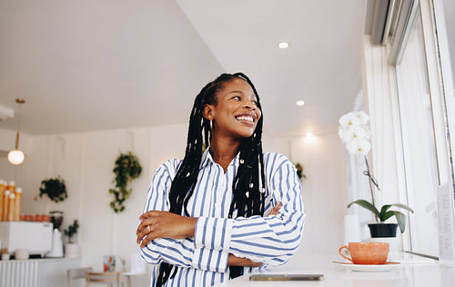 Smiling young businesswoman looking away thoughtfully in a cafe