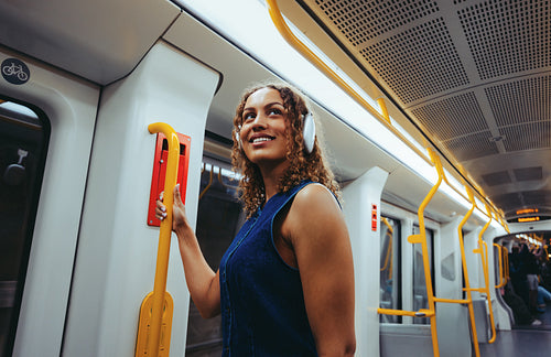 Curly-haired woman commutes by subway train wearing headphones
