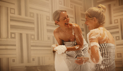 Mature woman and younger woman enjoying a foam bath in a hammam