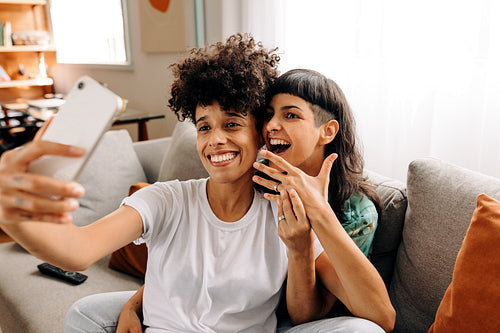 Engaged lesbian couple video calling their friends at home