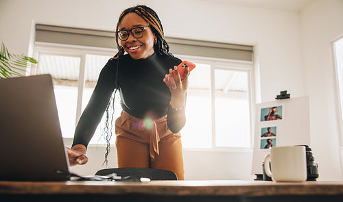 Creative young woman taking a phone call in her home office