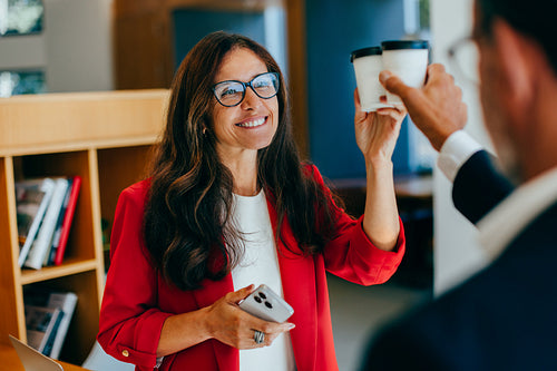 Professional colleagues exchanging smiles and coffee in a work environment