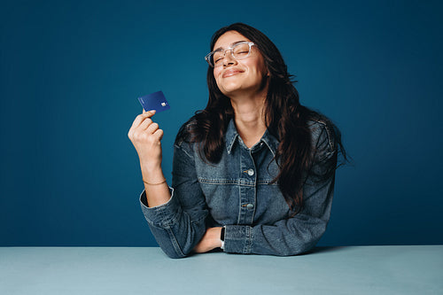 Confident young woman holding credit card in studio portrait