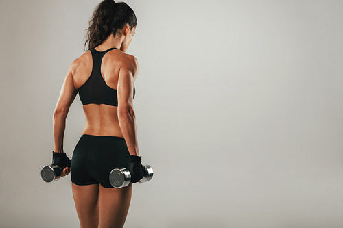Back of athletic woman holding weights