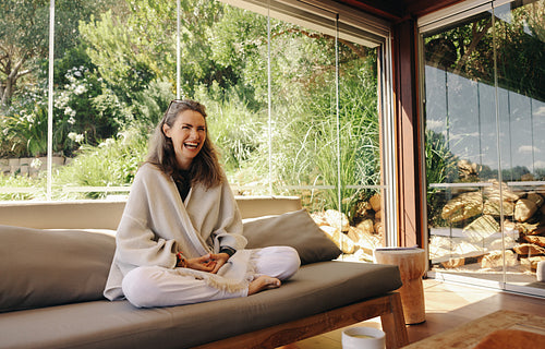 Cheerful senior woman meditating on a couch
