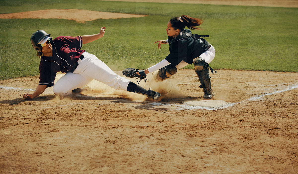 Base runner slides safely into home plate as the catcher attempts a ta ...