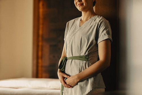 Professional masseuse in spa uniform prepared for a relaxing treatment session