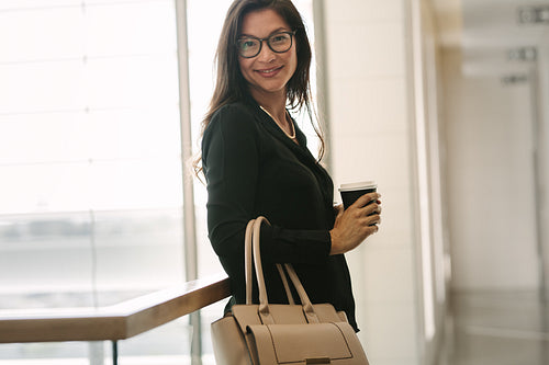 Business woman standing by a railing with coffee