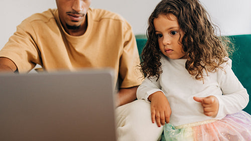 Dad showing his daughter an educational video on a laptop