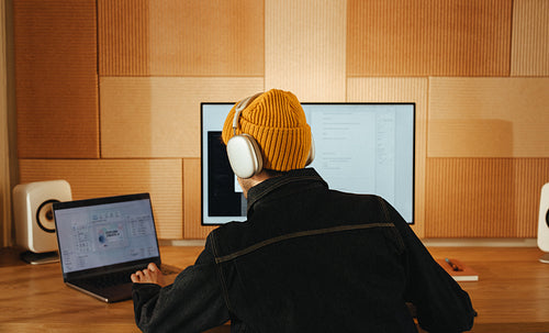 Man works at a computer desk with headphones in a home office