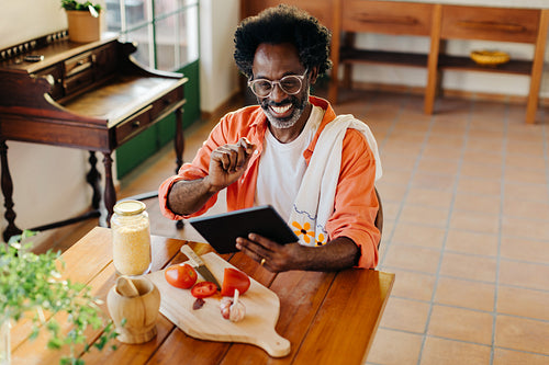 Brazilian man making a traditional homemade meal with digital tablet at home