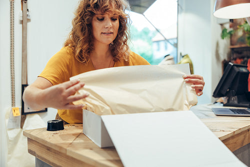 Fashion store owner packing a box for delivery
