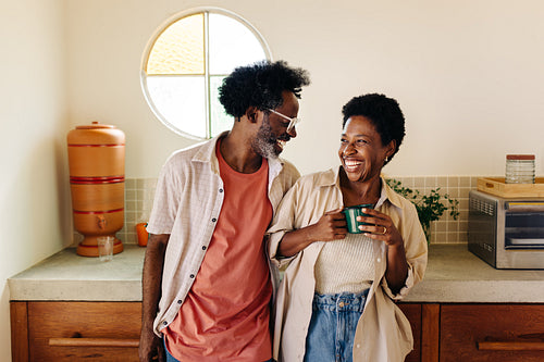 Afro Brazilian couple laughing together in the kitchen, enjoying their love